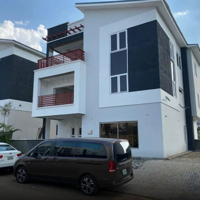 A completed white and charcoal duplex on a paved compound